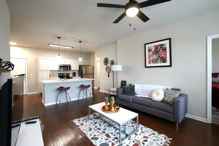 Modern open-concept living area with sleek kitchen and stylish decor, featuring a cozy sofa, elegant coffee table, and contemporary lighting.
