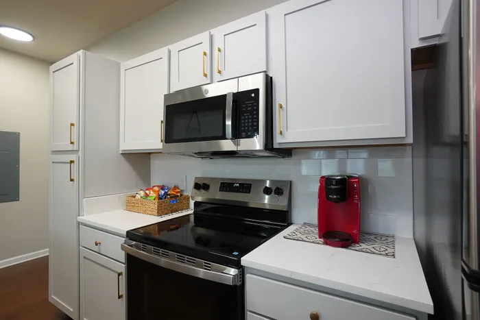 Modern kitchen with sleek white cabinets, stainless steel appliances, and elegant countertops. Bright and inviting space perfect for culinary creations.