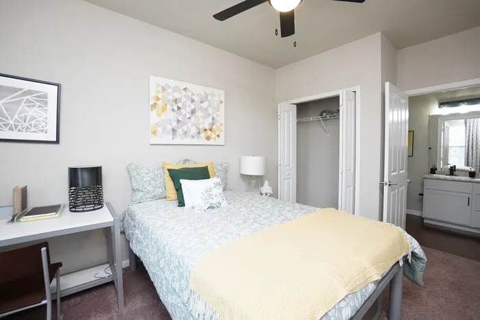 Inviting bedroom setup with modern decor, featuring a cozy bed, stylish artwork, and a convenient workspace.