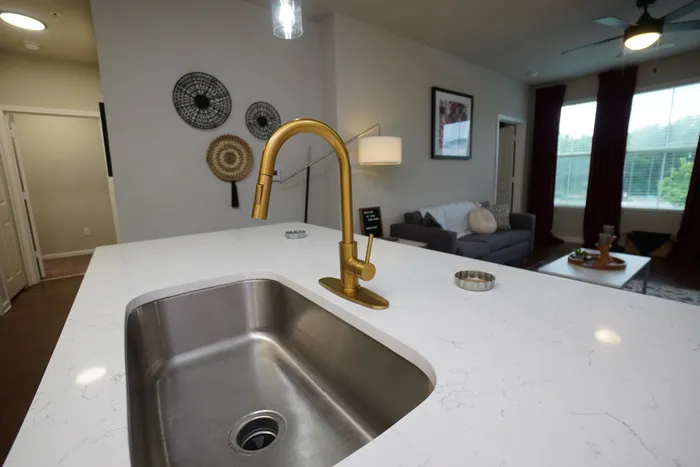 Modern apartment with elegant open-plan kitchen featuring a sleek faucet, chic living area, and large windows offering natural light.