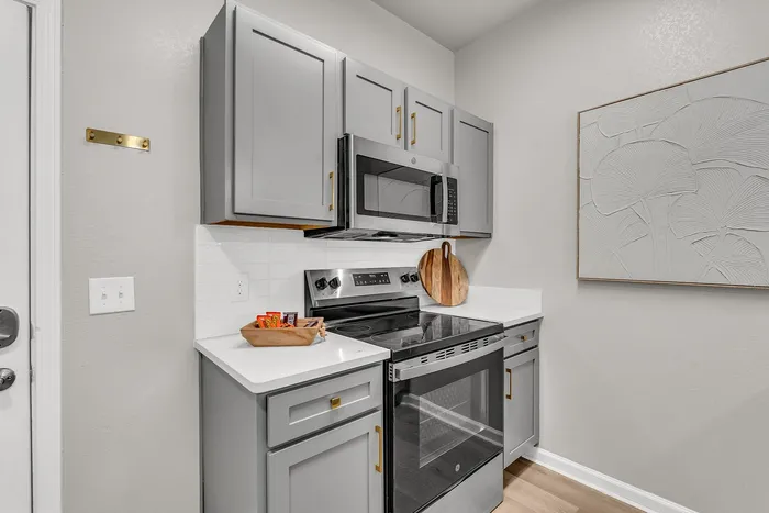 Chic modern kitchen with sleek gray cabinets, elegant countertops, and stainless steel appliances in a cozy corner layout.