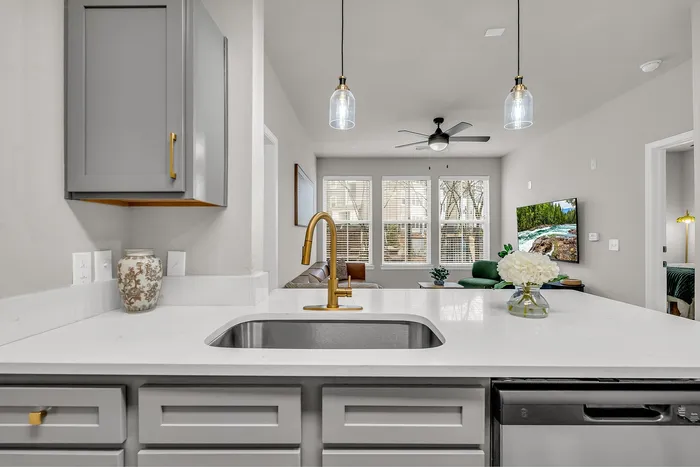 Elegant modern kitchen view leading into a chic living room with natural light and contemporary decor.