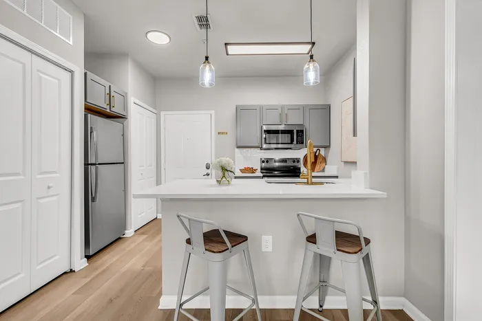Chic modern kitchen with sleek gray cabinets, elegant white countertops, and stylish pendant lighting, perfect for urban living.