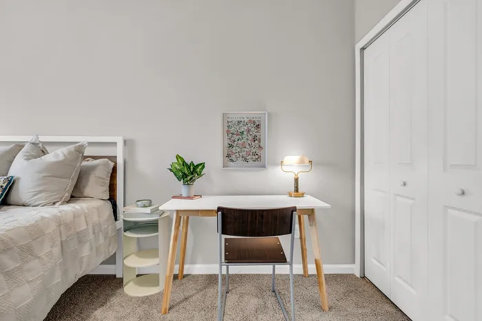 Chic bedroom corner with modern desk setup, cozy bed, and elegant lighting, perfect for relaxation and productivity.