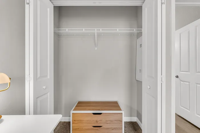 Contemporary closet space with organized shelving and modern drawer unit, ideal for maximizing storage in a sleek apartment.