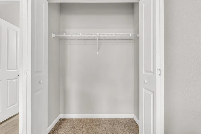 Bright, expansive closet with white double doors and ample shelving, ideal for organized living.