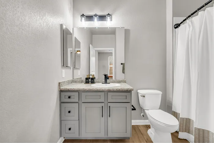 Modern bathroom featuring a sleek vanity with ample storage, elegant countertop, and bright lighting over the mirror.