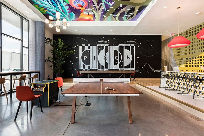 Chic modern lounge with artistic ceiling, ping pong table, and vibrant decor at Pixon apartment community.