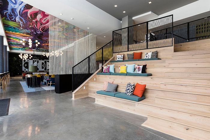Vibrant modern open-concept lobby with colorful ceiling art, plush tiered seating, and elegant lighting fixtures.