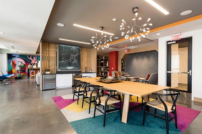Modern co-working space featuring vibrant decor, artistic wall mural, sleek furniture, and contemporary lighting.
