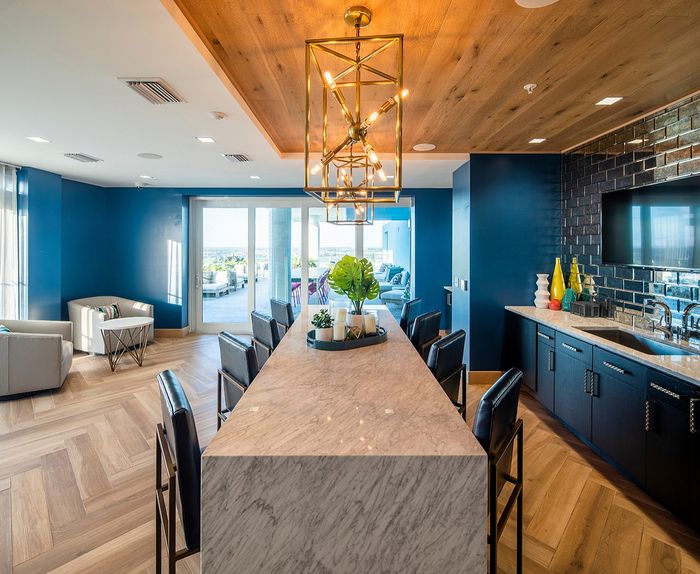 Luxurious kitchen and living area with modern finishes, featuring a marble island, stylish lighting, and scenic balcony views.
