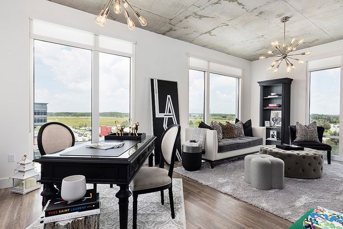Chic and modern apartment living room with stylish black furniture, plush seating, and expansive windows offering panoramic views.