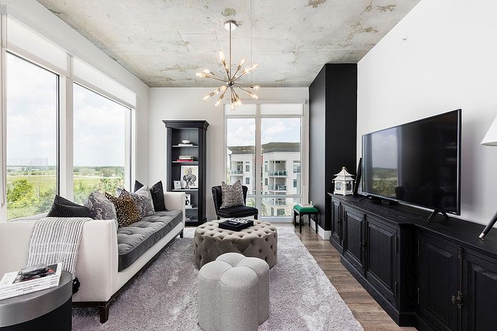 Modern living room with chic decor, large windows offering scenic views, and a stylish light fixture enhancing the contemporary ambience.