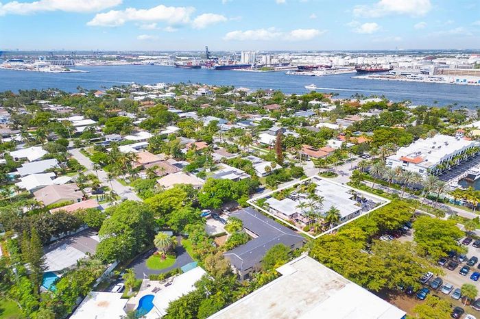 Breathtaking aerial view of a vibrant coastal neighborhood with lush greenery and sparkling waterways, perfect for serene living.