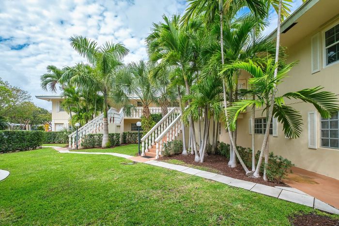 Charming tropical apartment complex with lush palm trees and inviting pathways for serene living.
