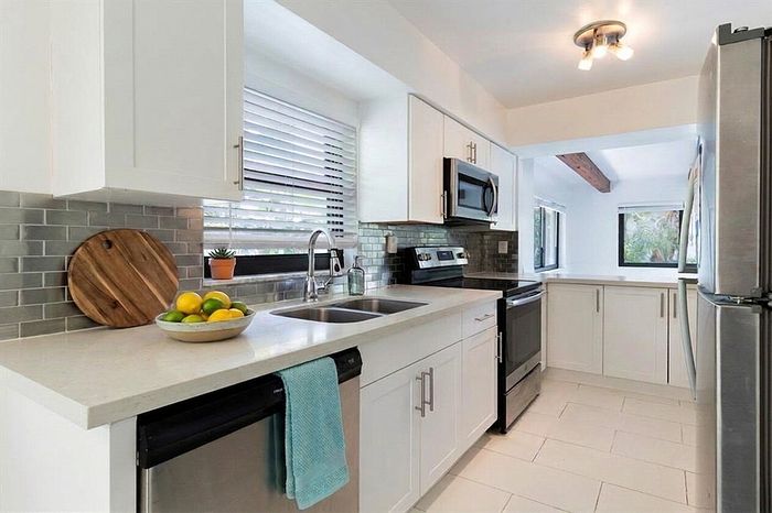 Bright modern kitchen with sleek stainless steel appliances, elegant subway tile backsplash, and large windows offering natural light.