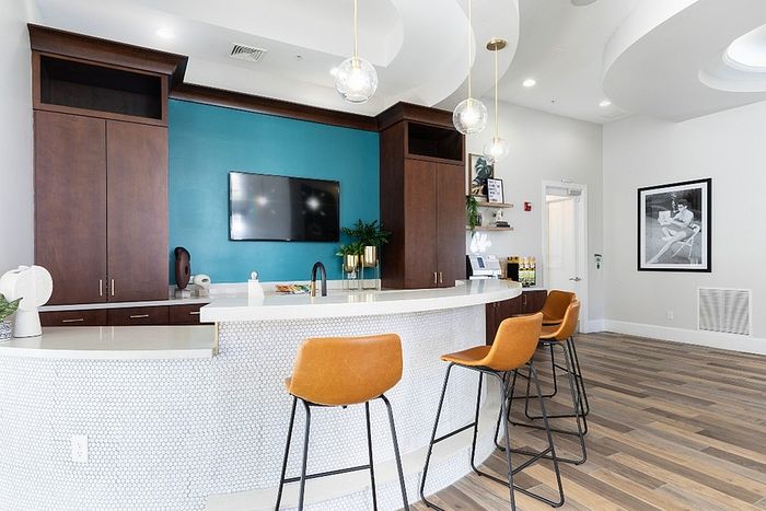 Modern lounge area with sleek curved counter, stylish pendant lights, and inviting wooden bar stools in a cozy ambiance.