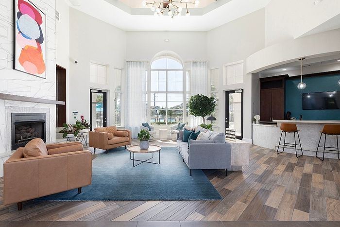 Spacious and bright modern living area with elegant sofas, chic decor, and a stylish bar. Large windows offer plenty of natural light and an inviting atmosphere.