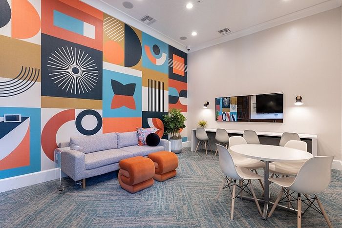 Vibrant living space featuring a modern sofa, bold geometric accent wall, and elegant dining area with contemporary chairs.