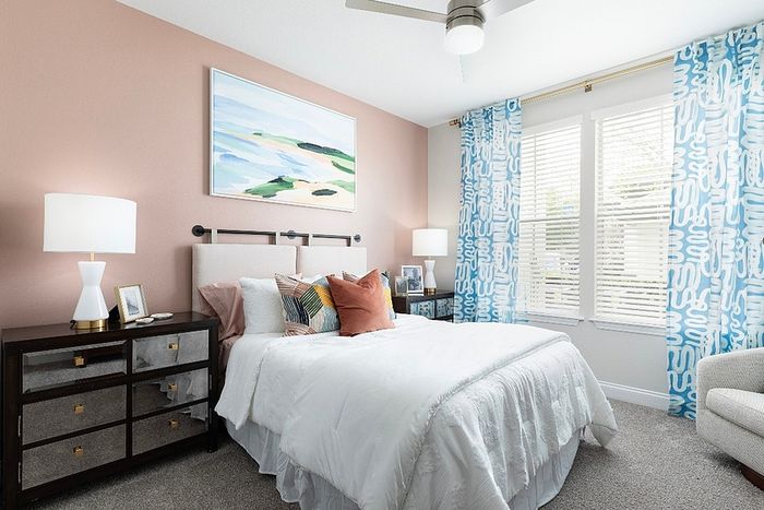 Inviting bedroom with a cozy bed, vibrant pillows, and stylish decor in a sunlit space.