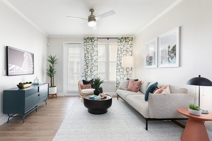 Modern living room with a stylish sofa, vibrant decor, and natural light from large windows, creating a serene and welcoming ambiance.