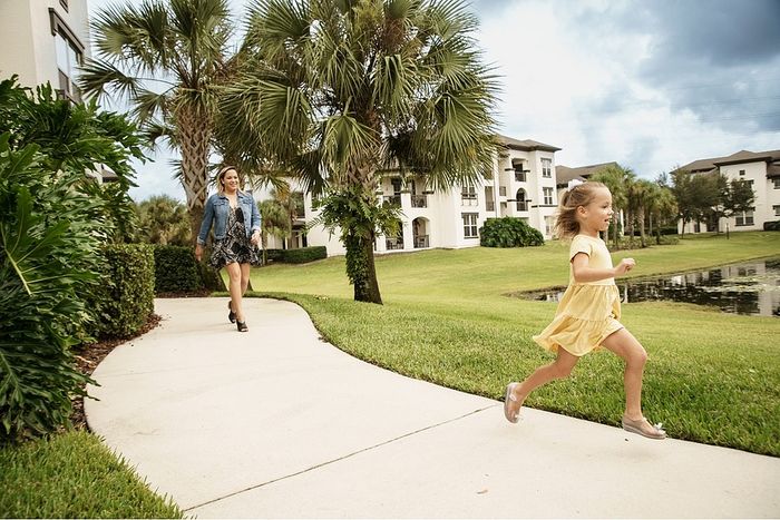 Vibrant apartment community with lush greenery, featuring a child joyfully running along a scenic pathway.
