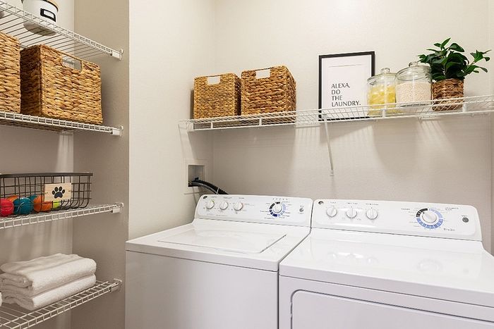 Chic laundry room with modern washer and dryer, stylish woven baskets, and organized shelving, creating a functional and elegant space.