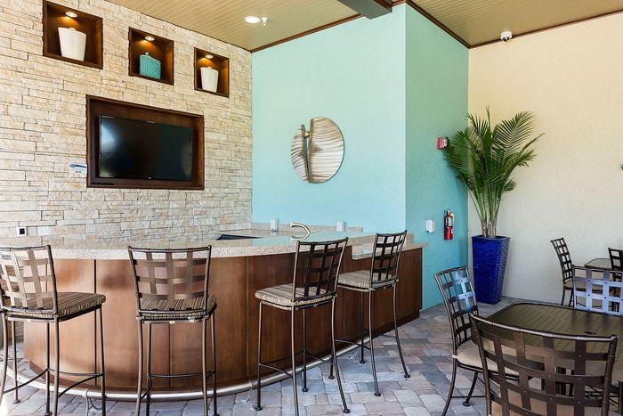 Chic outdoor lounge area with stylish bar seating, elegant stone wall, and modern decor elements.