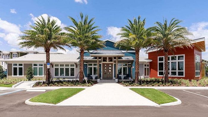 Bright and inviting apartment complex exterior with palm trees and modern architectural design, featuring large windows and vibrant landscaping.