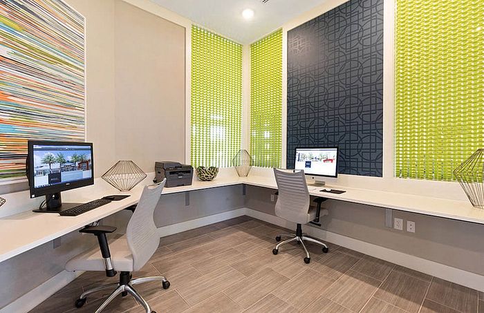 Modern and vibrant office space featuring sleek computers, stylish chairs, and colorful wall accents, perfect for productivity.