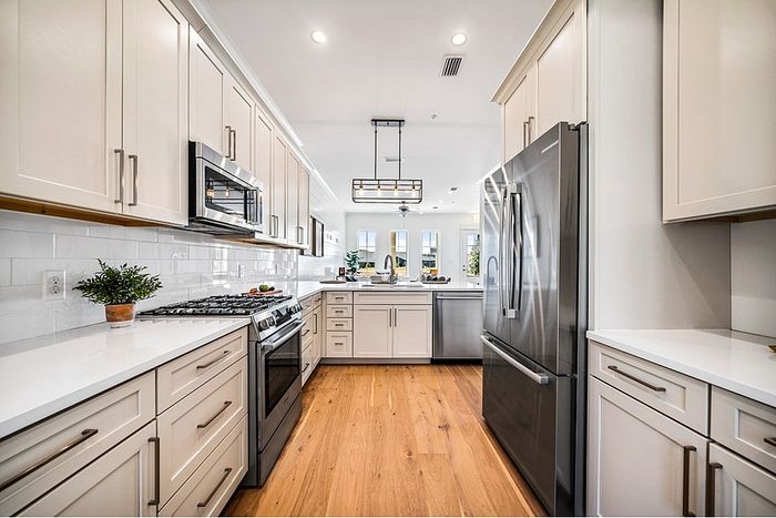 Contemporary kitchen with sleek stainless steel appliances, elegant cabinetry, and bright natural lighting.