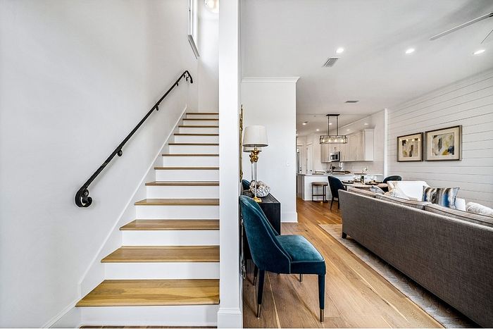Elegant modern interior showcasing a stylish open-concept living area with sleek hardwood floors and a cozy staircase leading to the upper level.