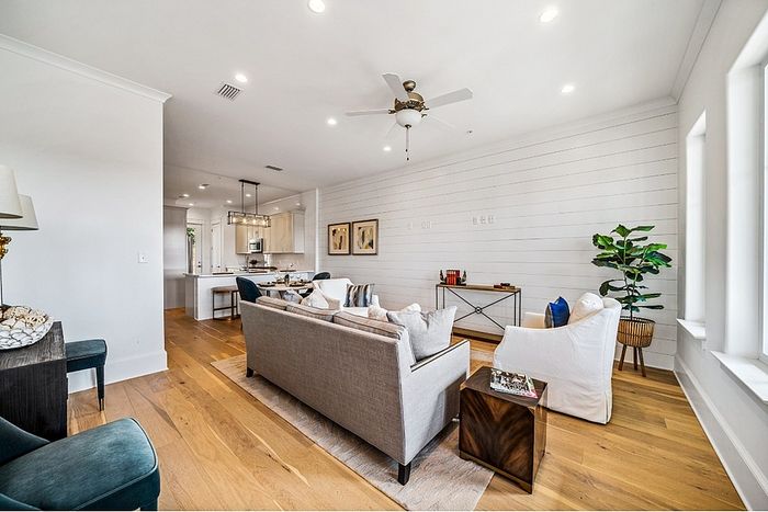 Bright and inviting open-concept living space with hardwood floors, cozy seating area, and a modern kitchen in the background.