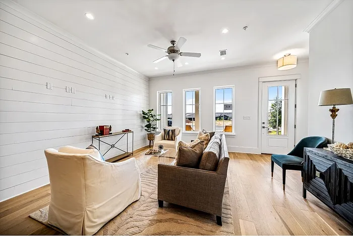 Bright and inviting living room with elegant decor, featuring a comfortable sofa, chic armchairs, and natural light pouring through large windows.