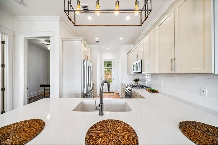 Modern kitchen with sleek white cabinets, stylish pendant lighting, and a spacious island countertop with built-in sink.