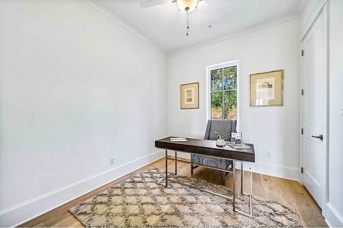 Bright and elegant home office space with a chic desk, plush chair, and natural light pouring through large windows, complemented by tasteful wall art and a cozy rug.