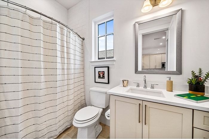 Bright modern bathroom with elegant vanity, large mirror, and natural light through window.