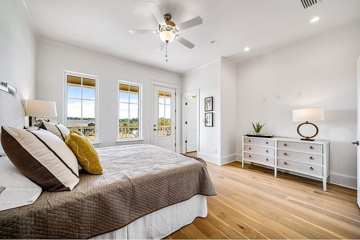 Elegant bedroom with abundant natural light, stylish ceiling fan, and cozy bedding, offering a serene retreat and picturesque views.