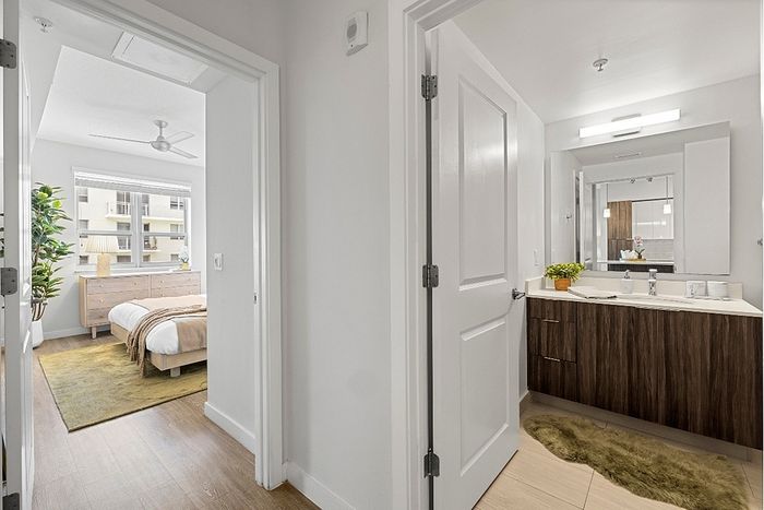 Bright and inviting view of a modern bedroom and bathroom, featuring sleek wooden flooring and elegant decor.