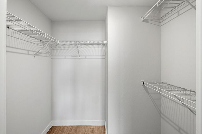 Spacious walk-in closet with sleek wire shelving and elegant hardwood floors, perfect for ample storage.