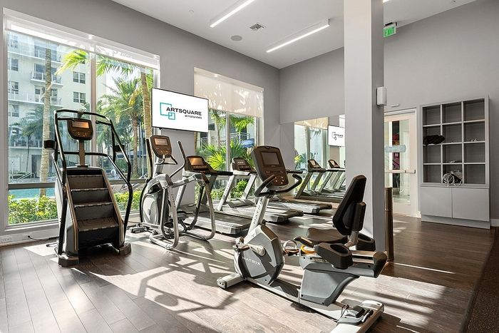 Modern fitness center with state-of-the-art equipment and floor-to-ceiling windows overlooking lush greenery.