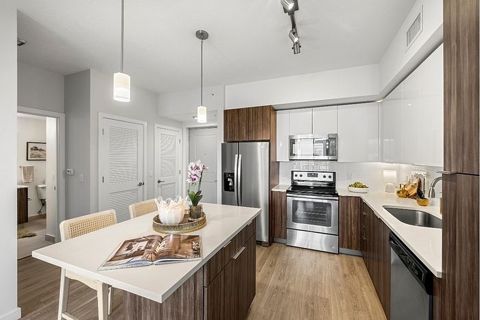 Modern kitchen interior with sleek wooden cabinetry, stainless steel appliances, and a stylish island bar with pendant lighting.