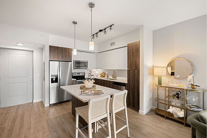 Elegant kitchen with modern stainless steel appliances, chic island, and stylish lighting in an inviting open-concept living space.