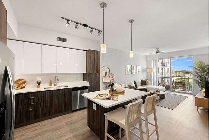 Modern open-concept kitchen and living room with sleek cabinetry, elegant island, and a bright balcony view.