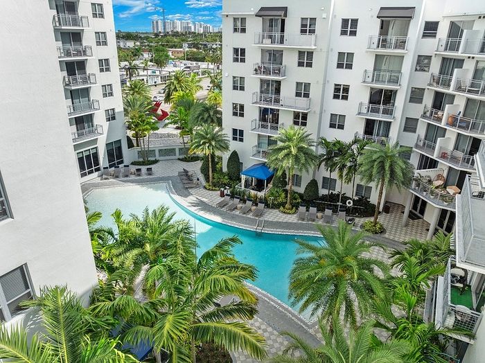 Luxurious apartment complex with a stunning poolside view surrounded by lush palm trees, perfect for relaxation and city living.