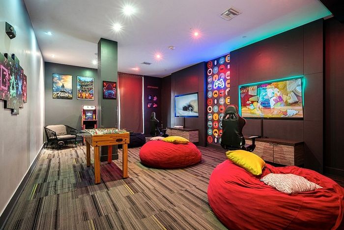 Vibrant entertainment room featuring colorful bean bags, gaming chairs, a foosball table, and a large TV with ambient lighting, perfectly designed for relaxation and fun.