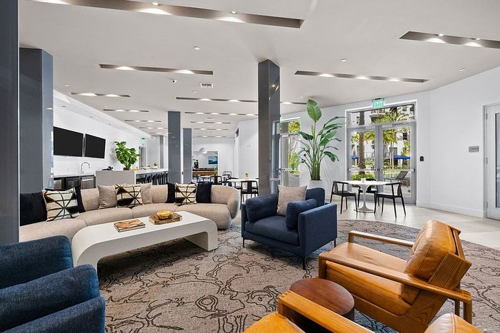 Luxurious open-concept lounge area with modern furniture, elegant decor, and abundant natural light from large windows.