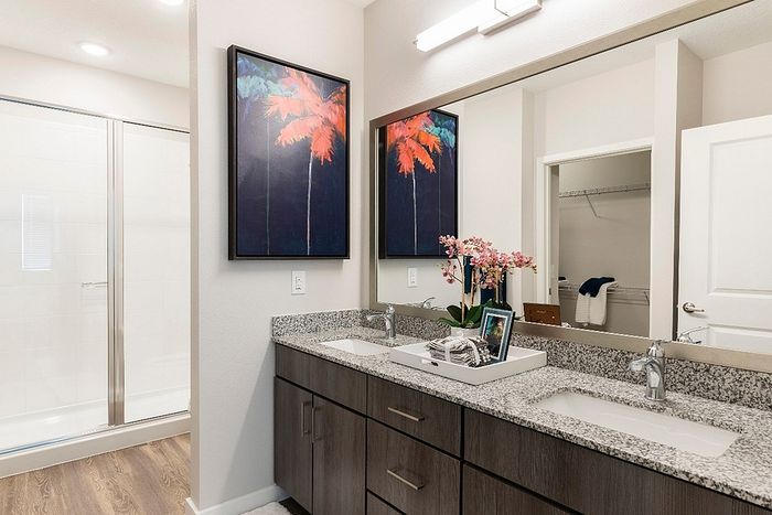 Elegant modern bathroom featuring a double granite vanity, stylish artwork, and refined decor with ample storage space.