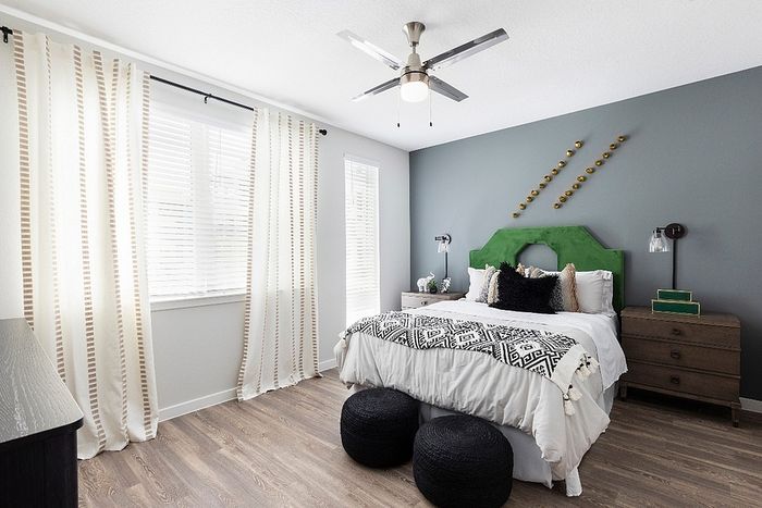 Modern bedroom with stylish decor featuring a green headboard, patterned throw, and elegant wall art, offering a serene and welcoming ambiance.