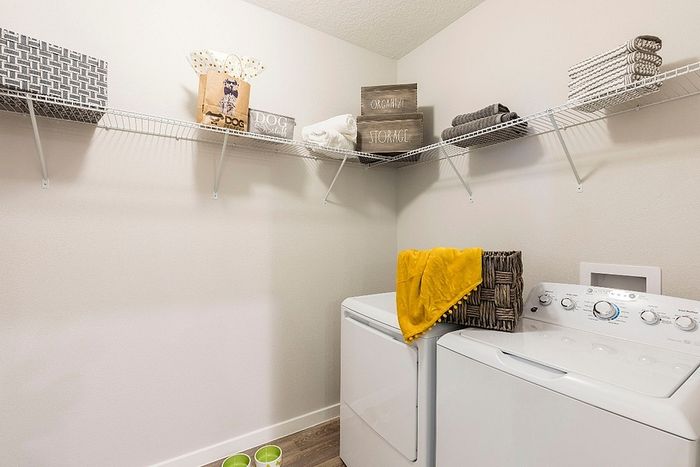 Bright and organized laundry room featuring modern washer and dryer with ample storage on sleek wire shelving.